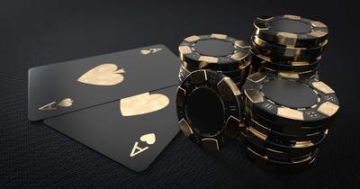 Black and gold poker chips and black and gold playing cards are seen on a black background.